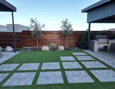A backyard with grass and concrete tiles